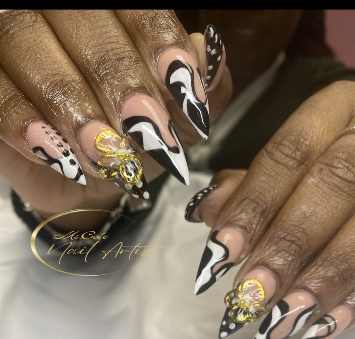Black and white stiletto nails with a gold 3D flower