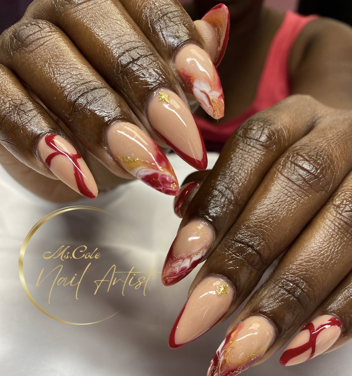 Almond nails with red swirl and gold star accents